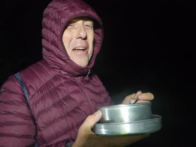 Soup and noodles on the way down to Dover via the North Downs. Dave looks into the camera with a pan of steaming soup and noodles. It's pitch black in the early hours of the morning.