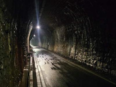 In one of the disused railway tunnels the cycle way follows through Dortmund, Germany. Nice and cool on a hot day. Dark stone railway tunnel converted to cycle path, lit by spaced ceiling lights.