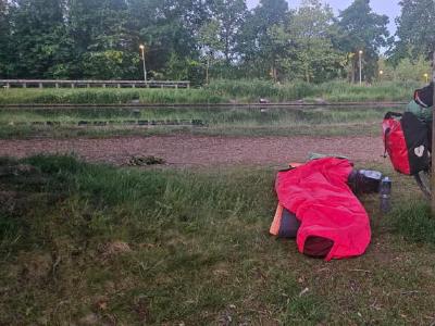 Bivy spot on day 10. On the north bank of the canal that runs through Pelt in the Netherlands. During the night some bloke was shouting out for 'Lin' for what seemed like ages. Hope they found them. Bivy bag, bike and gear beside a canal on grassy bank at dawn.