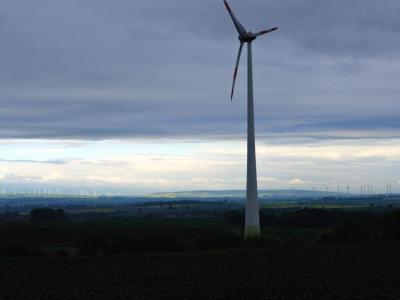 See all the turbines on the horizon. There were hundreds of them in this area. Single large wind turbine in foreground with many more on the far horizon.