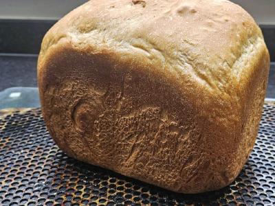 Plain White Loaf Whole baked white loaf from a bread machine, cooling on a perforated tray.
